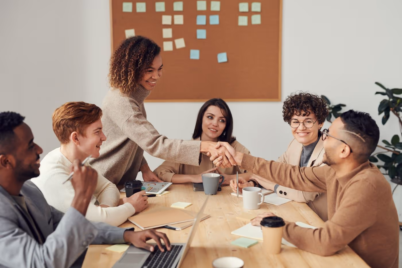 Coworkers around a meeting table as two of them shake hands