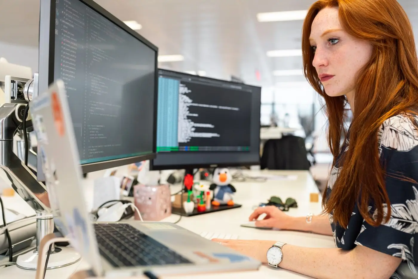 Developer working at a desk with two monitors showing code