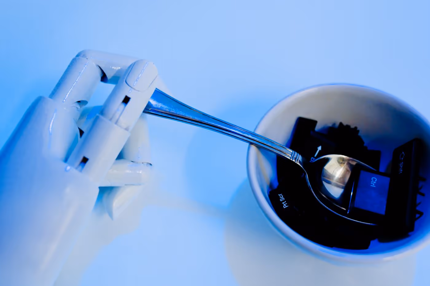 Robotic hand holding a spoon over a bowl of computer keys